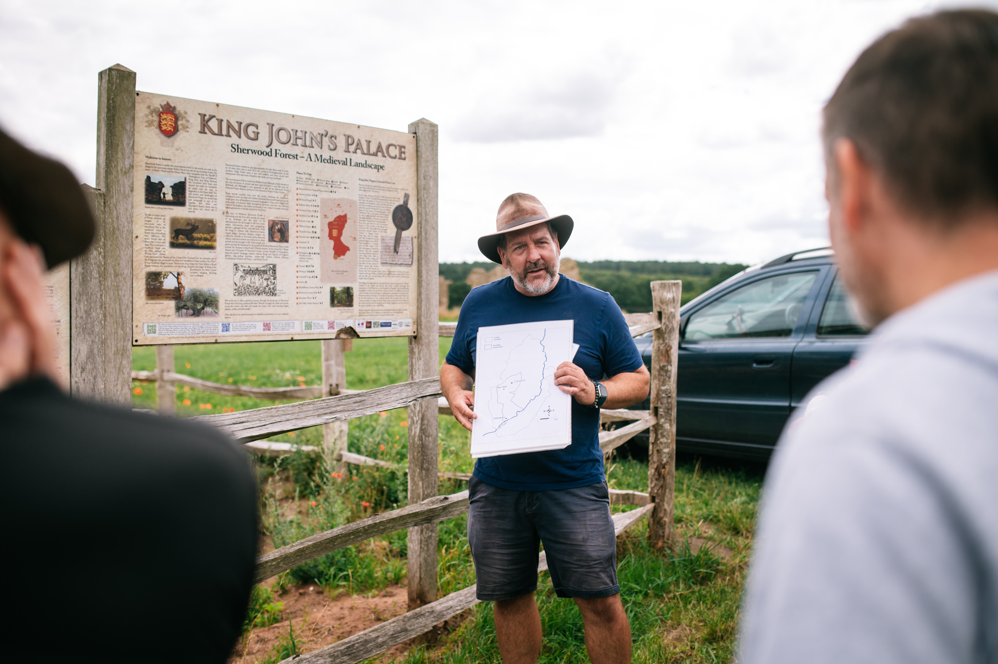 archaeologist stood in front of info boards holding a print out teaching students about the site