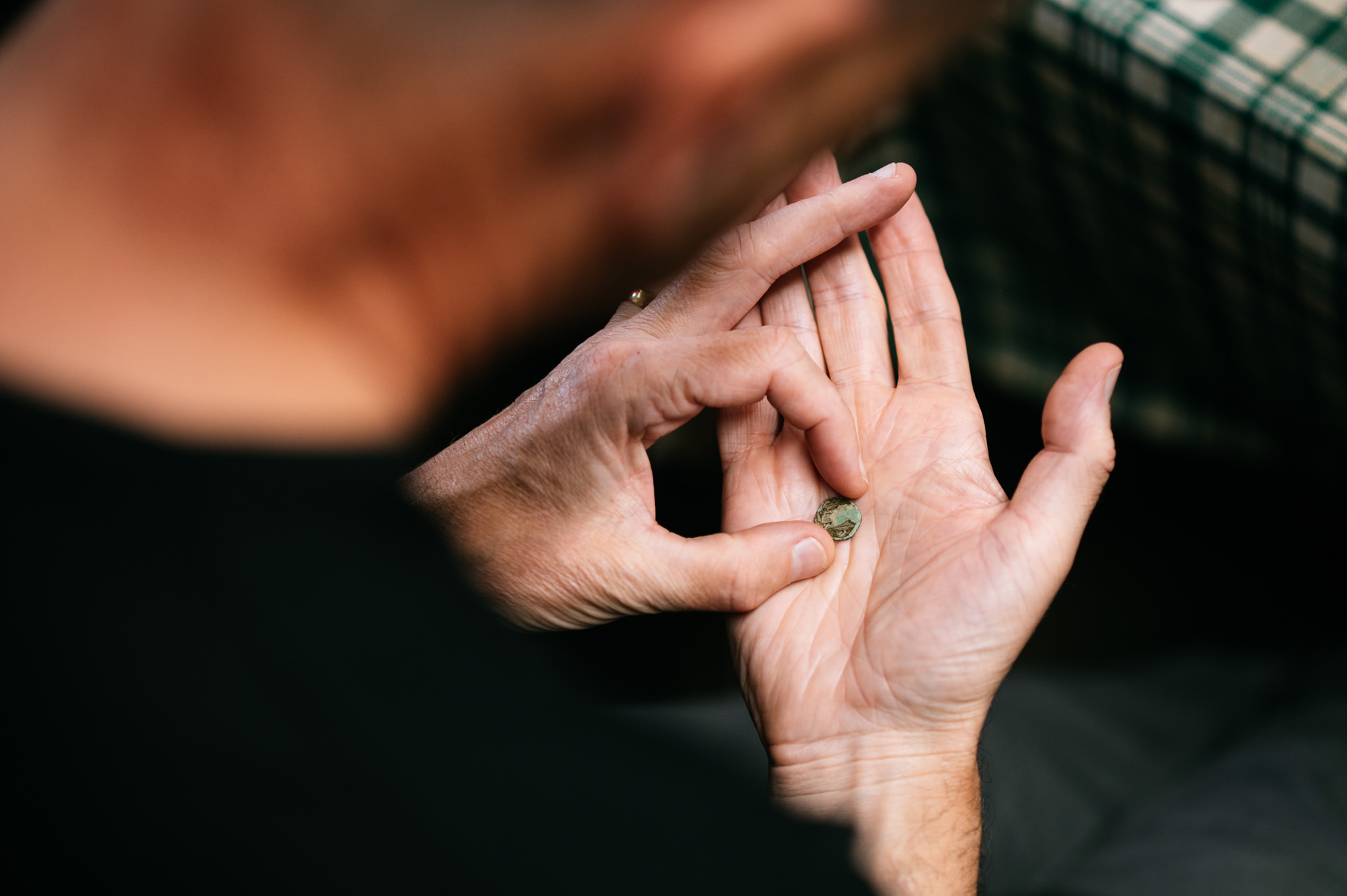 close up of hands examining a small coin