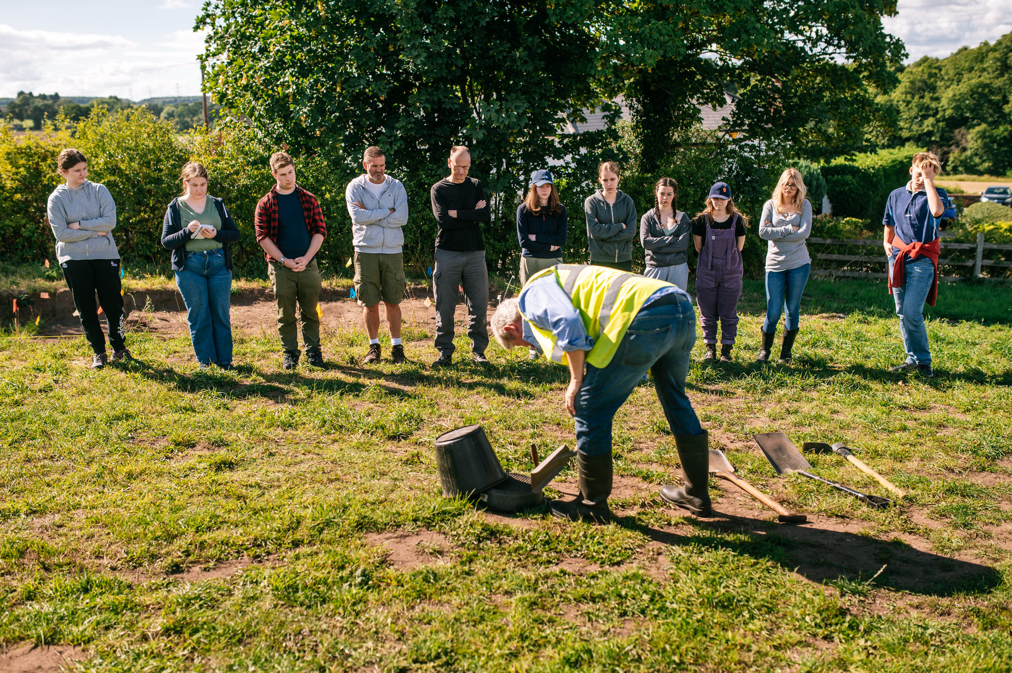 archaeological field school students being shown the tools of the trade
