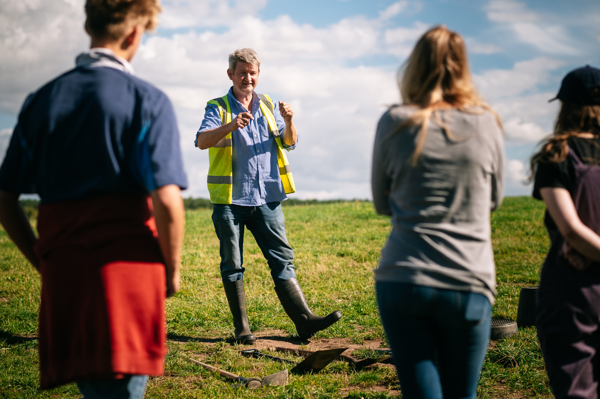 archaeologist in high vis vest teaching students at the side of the trench
