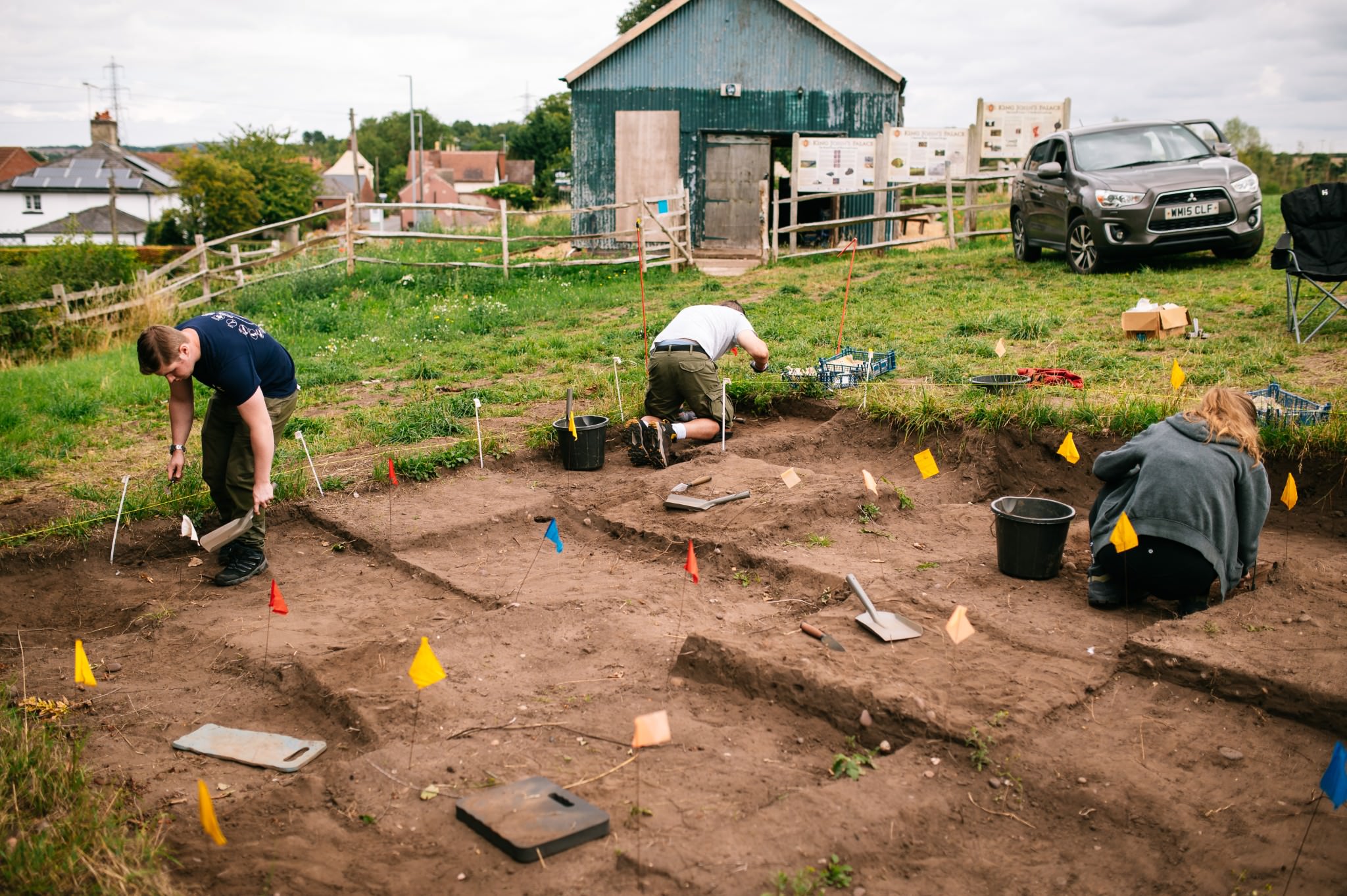 field school delegates digging in marked out squares in the trench