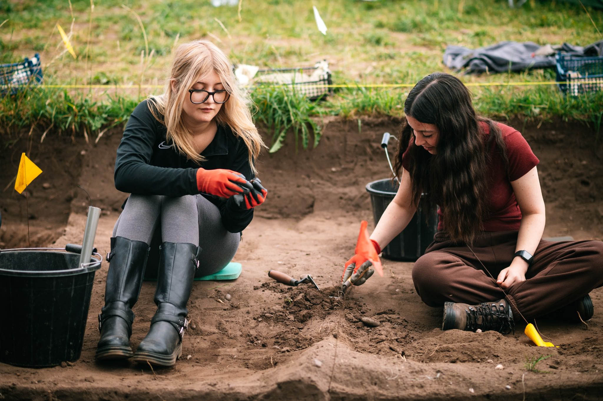 two young archaeology students sat in a trench