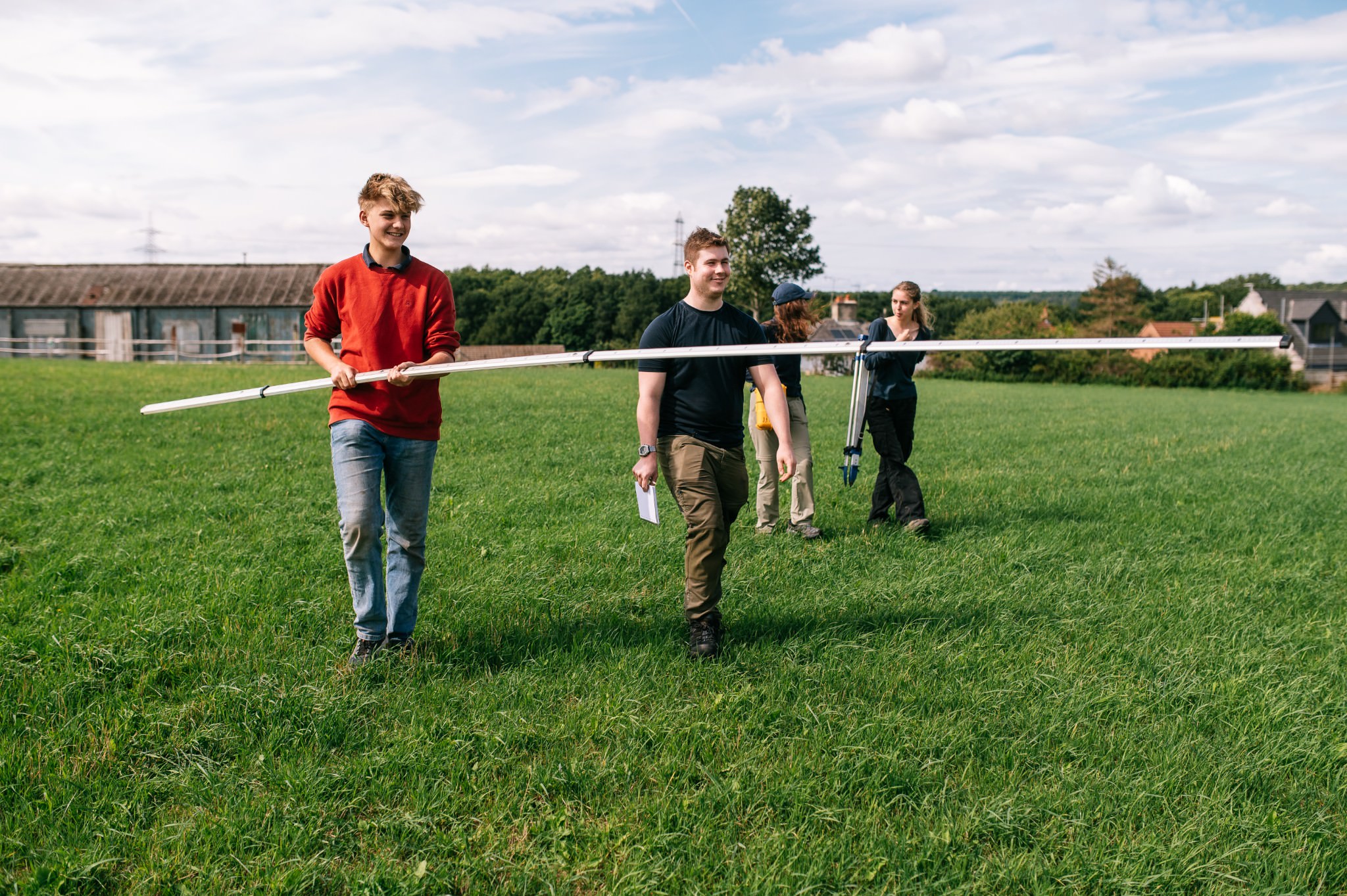 man in a red sweater holding an extended measuring stick