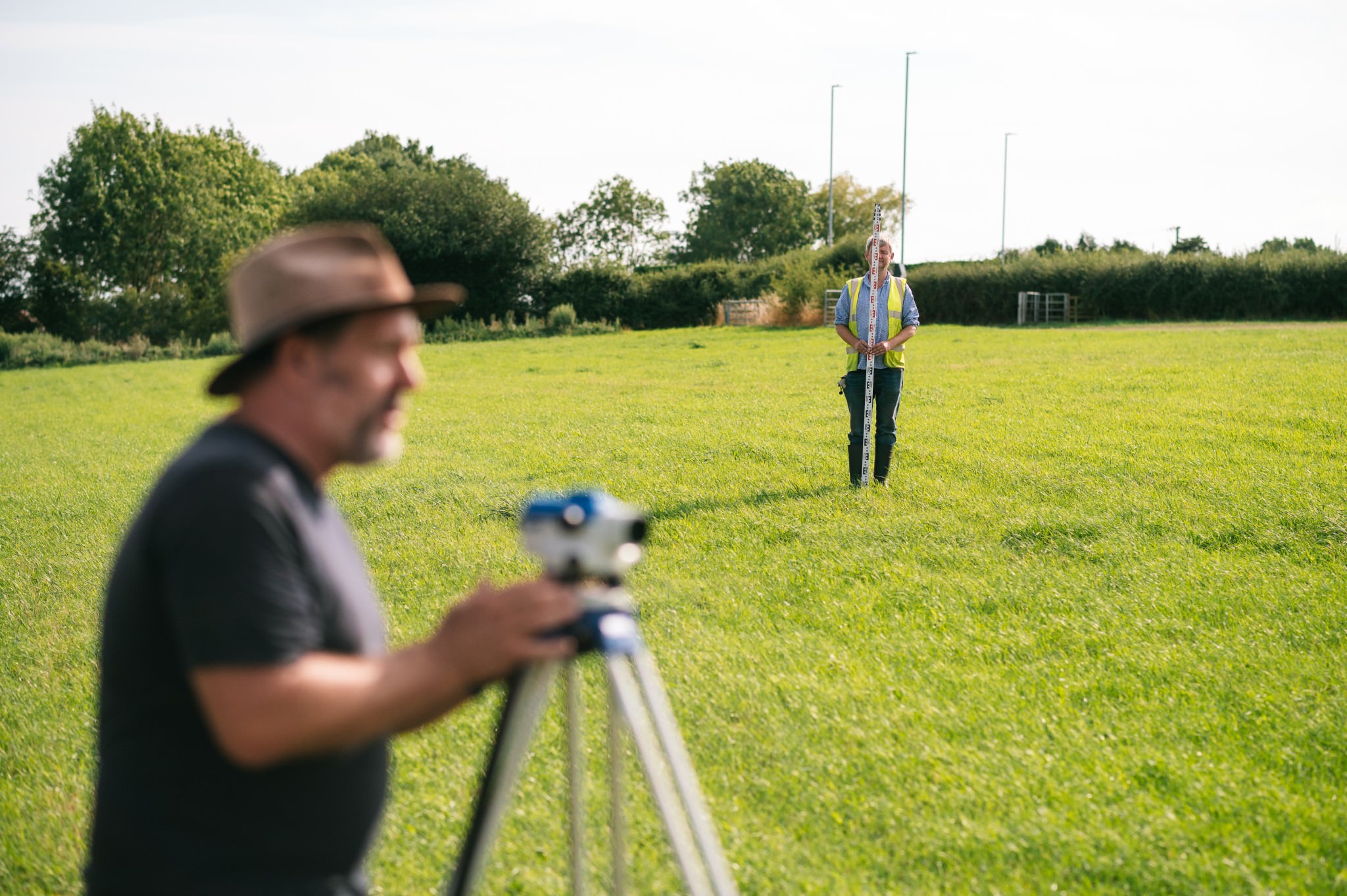 archaeologists teaching students how to survey using a dumpy level and a measuring staff